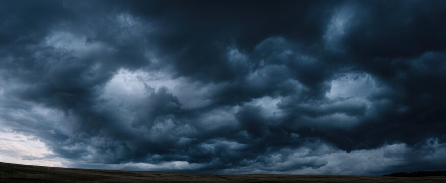 Fototapeta The dark storm clouds gathering over a vast landscape at twilight.