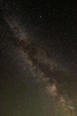 Against a dense field of stars and the glowing path of the Milky Way, a single streak cuts through—like a whispered wish flung across the dark canvas of eternity