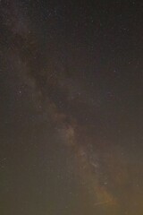 Against a dense field of stars and the glowing path of the Milky Way, a single streak cuts through—like a whispered wish flung across the dark canvas of eternity