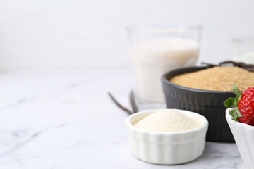 Different ingredients for panna cotta. Milk, sugar, vanilla and strawberries on white marble table, closeup. Space for text