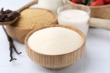 Different ingredients for panna cotta. Milk, sugar, vanilla, chocolate and strawberries on white tiled table, closeup