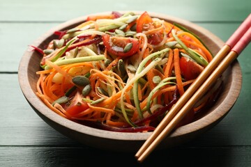 Tasty vegetable noodles served on green wooden table, closeup