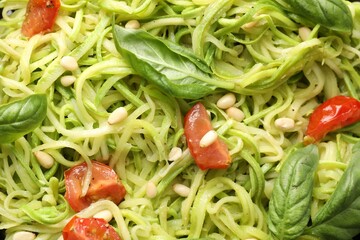 Tasty zucchini noodles with tomatoes, pine nuts and basil, closeup