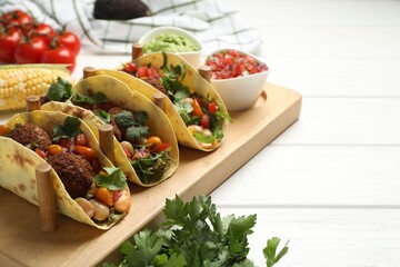 Tasty vegetarian tacos with falafel served with salsa and guacamole on white wooden table, closeup....