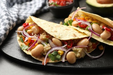 Tasty vegetarian tacos with beans and quinoa served on grey table, closeup
