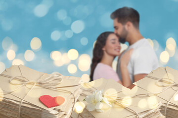 Romantic young couple and love letters, bokeh effect. Woman and man hugging against light blue...