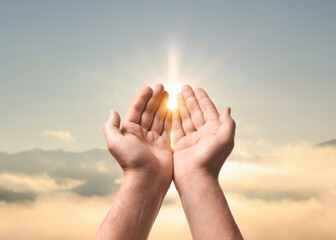 Hope. Man holding hands against sky with bright sun in mountains, closeup