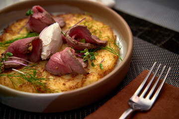 Deliciously Plated Dish Showcasing Tender Roasted Meat on a Crisp Bed of Golden Potato, Garnished with Fresh Herbs and Creamy Topping