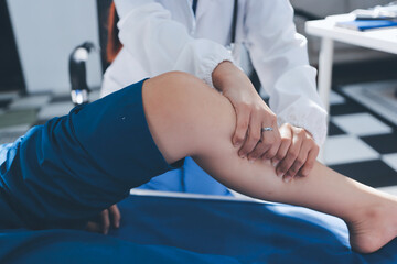 Female doctor hands doing physical therapy By extending the leg and knee of a male patient