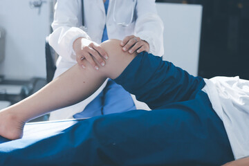 Female doctor hands doing physical therapy By extending the leg and knee of a male patient