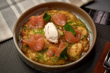 Deliciously Crafted Potato Dish with Smoked Salmon, Herbs, and Creamy Element, Perfectly Presented in a Round Serving Bowl for an Appetizing Delight