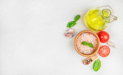 Cooking ingredients with pink salt, tomatoes, garlic, basil, and olive oil on white background. top view.