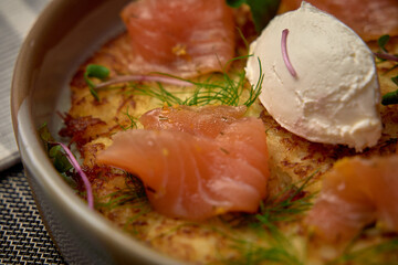 A scrumptious dish featuring delicate smoked salmon atop a golden crispy base, garnished with fresh...
