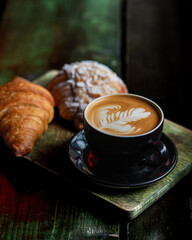 Croissants and cup of black coffee on black background. Selective focus