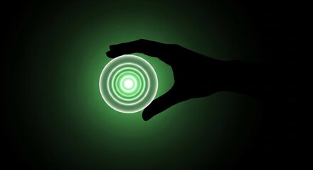 Silhouette of a hand holding a vibrant green glowing energy orb on a dark background.