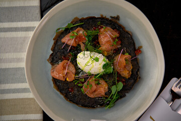A Gourmet Dish Featuring Delicate Smoked Salmon, Poached Egg, and Fresh Microgreens Nestled on a...