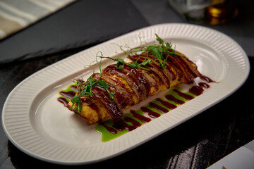 A beautifully presented plate of gourmet omelette drizzled with rich sauce and garnished with fresh herbs, showcasing culinary artistry and elegant dining.