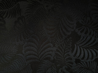 Elegant black fabric texture with embossed tropical leaf pattern. Sophisticated dark botanical...