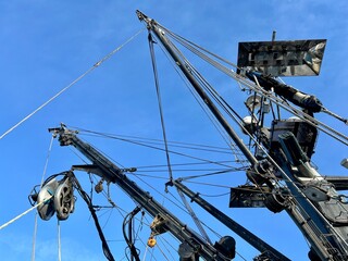 Upward view of fishing boat mast and rigging system with multiple cables, pulleys, and maritime...
