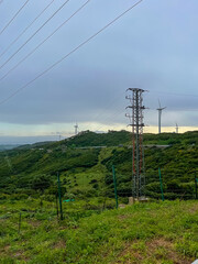 Power transmission lines and electric tower in a green valley. Concept of energy crisis, electricity supply, blackouts and sustainable infrastructure.