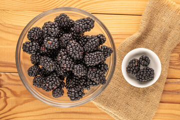 Sweet ripe blackberries on a wooden table, close-up, top view.