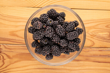 Sweet ripe blackberries on a wooden table, close-up, top view.