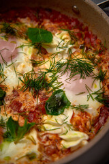 A Deliciously Prepared Dish of Eggs Poached in Spicy Tomato Sauce Topped with Fresh Herbs and Greens for a Flavorful Culinary Experience