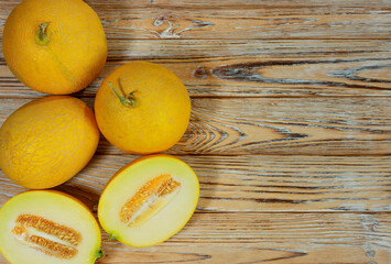 Whole and Halved Yellow Melons on Rustic Wooden Surface