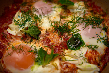 A Deliciously Garnished Dish of Shakshuka with Bright Yolks, Fresh Herbs, and a Flavorful Tomato...