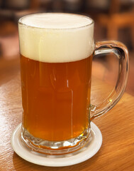 Mug with beer and foam on a blurred background. Close-up