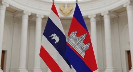 Depicts the flags of Thailand and Cambodia displayed indoors indicating diplomatic relations and