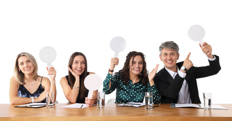 Panel of happy judges with blank score signs at table on white background