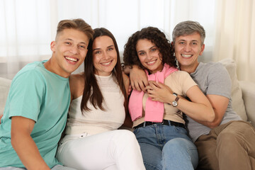 Happy friends hugging and having fun on sofa at home