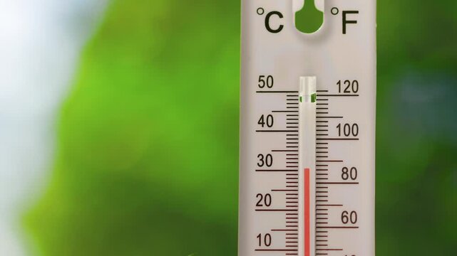 A vertical outdoor thermometer with dual Celsius and Fahrenheit scales showing rapid temperature rise from normal to overheat, indicating heatwave or extreme weather conditions