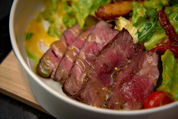 A Close-Up View of Succulent Slices of Juicy Steak Accompanied by Fresh Greens and Colorful Vegetables, Creating a Delicious Gourmet Meal Experience