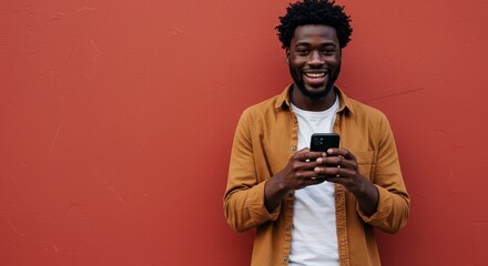 Happy Black Man Holding Phone with Red Wall Background Smiling