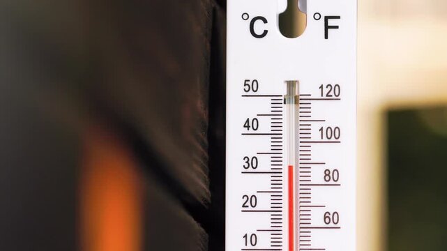 A vertical outdoor thermometer with dual Celsius and Fahrenheit scales showing rapid temperature rise from normal to overheat, indicating heatwave or extreme weather conditions