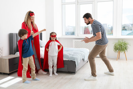 Parents and children in superhero costumes playing at home