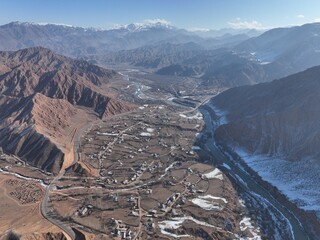 A broad aerial perspective showing an extensive village in a wide valley, with a river and...