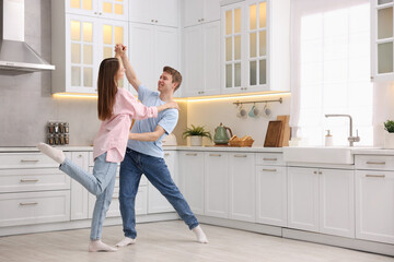 Happy young couple dancing together in kitchen