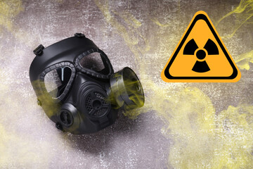 Radiation threat. Gas mask, radioactive sign and smoke on grey background, top view