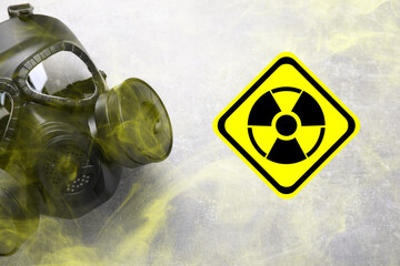 Radiation threat. Gas mask, radioactive sign and smoke on grey background, top view
