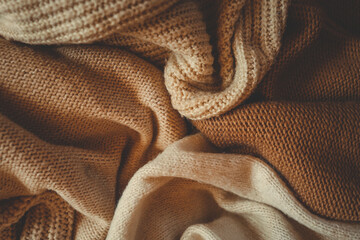 Close-up of soft, cozy, knitted beige and brown woolen blankets. Texture and folds of warm fabric...