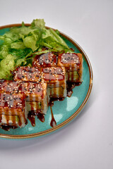 A delicious arrangement of sushi rolls topped with sweet sauce and sesame seeds, served alongside...