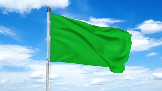 Blank green flag waving in the wind against a cloudy blue sky