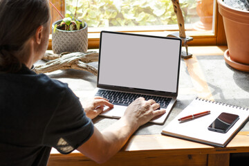 Man Working from Home on Laptop near Window with Green View