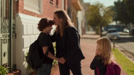 Mother saying goodbye to children before school, family morning routine