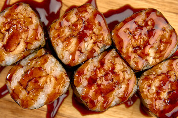 Delicious Sushi Rolls Glazed with Sweet Sauce Perfectly Arranged on a Wooden Surface for a Tantalizing Culinary Experience