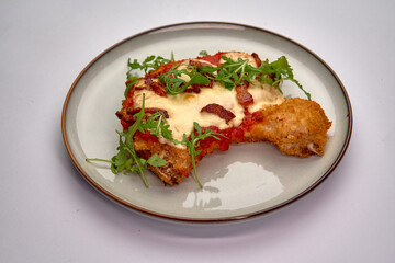 A Deliciously Baked Chicken Dish Featuring Crispy Coating, Rich Tomato Sauce, Melted Cheese, and Fresh Arugula on a Clean Plate