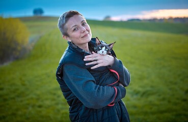 Woman Walking Outdoors with Canadian Sphynx Cat in Arms